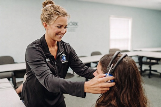 Technician assisting test subject with headphones